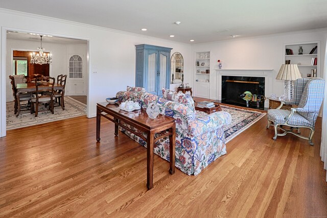 68 Hawthorne Dr, Fairfield, CT 06825 - living room with built in features, a chandelier, light wood-type flooring, ornamental molding, and a high end fireplace