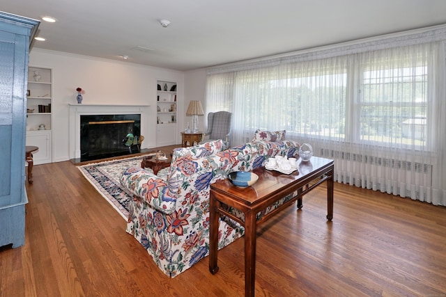 68 Hawthorne Dr, Fairfield, CT 06825 - living area with built in shelves, wood finished floors, a fireplace, and ornamental molding