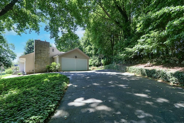 68 Hawthorne Dr, Fairfield, CT 06825 - view of side of home with driveway, a chimney, and an attached garage