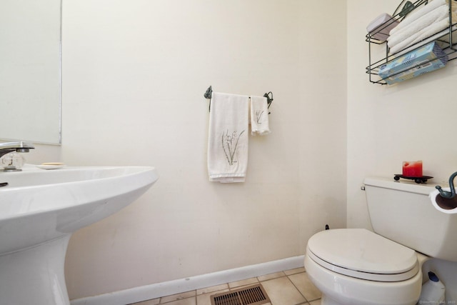 half bathroom featuring baseboards, toilet, tile patterned flooring, and a sink