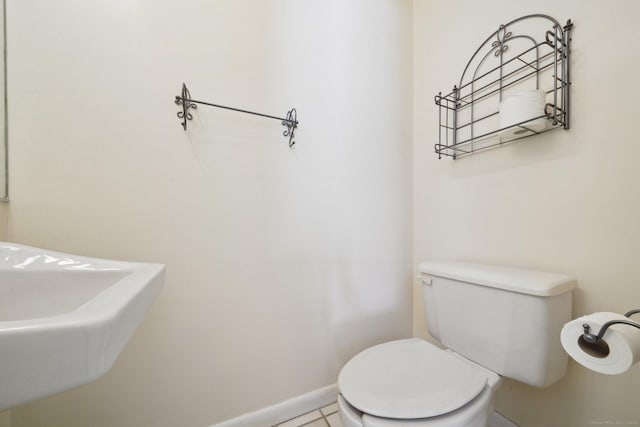 bathroom with a sink, toilet, and baseboards
