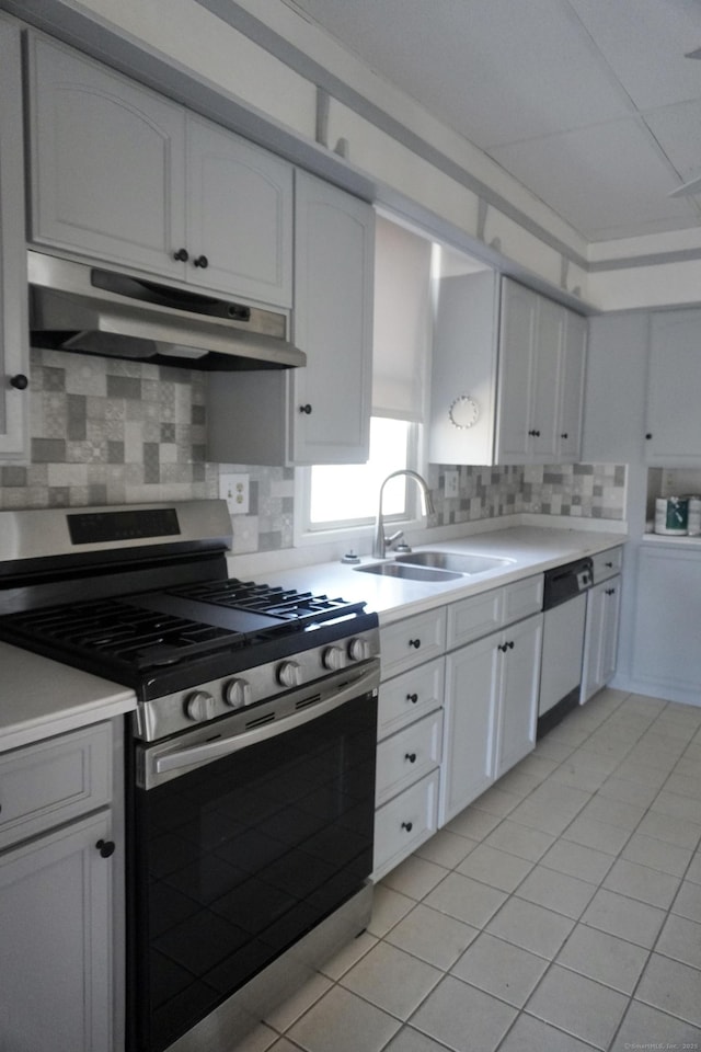 kitchen with dishwashing machine, a sink, light countertops, under cabinet range hood, and stainless steel gas stove
