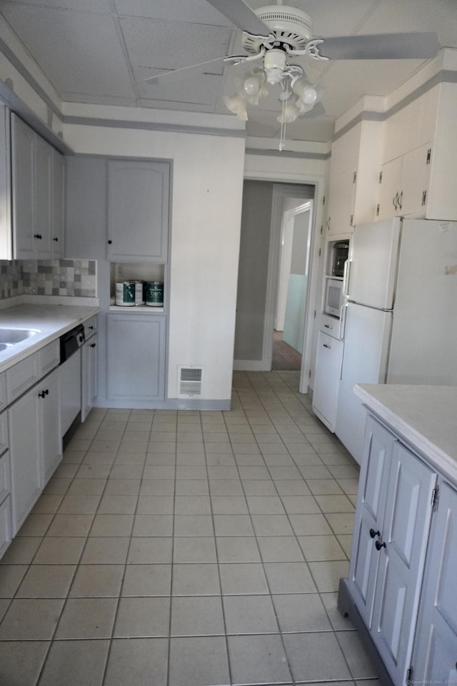kitchen featuring visible vents, light countertops, decorative backsplash, freestanding refrigerator, and a ceiling fan