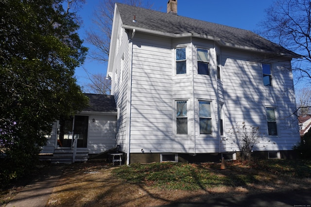 view of side of property featuring a shingled roof and a chimney