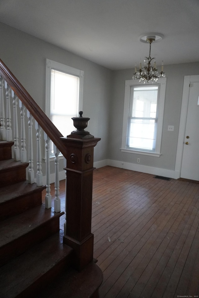 interior space featuring hardwood / wood-style floors, a notable chandelier, and baseboards