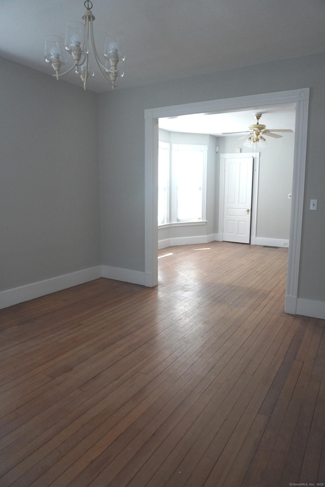 unfurnished room with hardwood / wood-style flooring, ceiling fan with notable chandelier, and baseboards