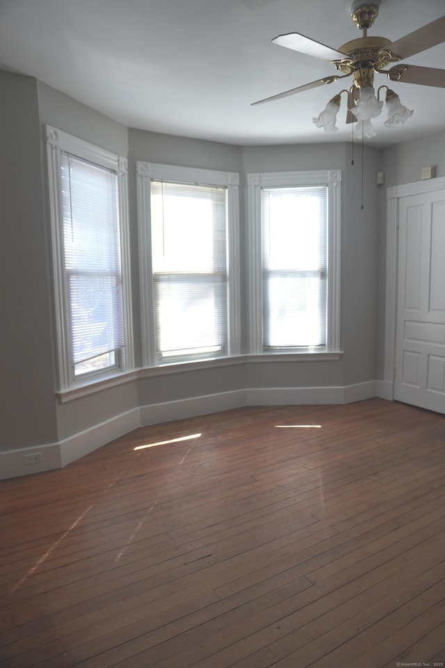 empty room featuring baseboards, a ceiling fan, and wood-type flooring
