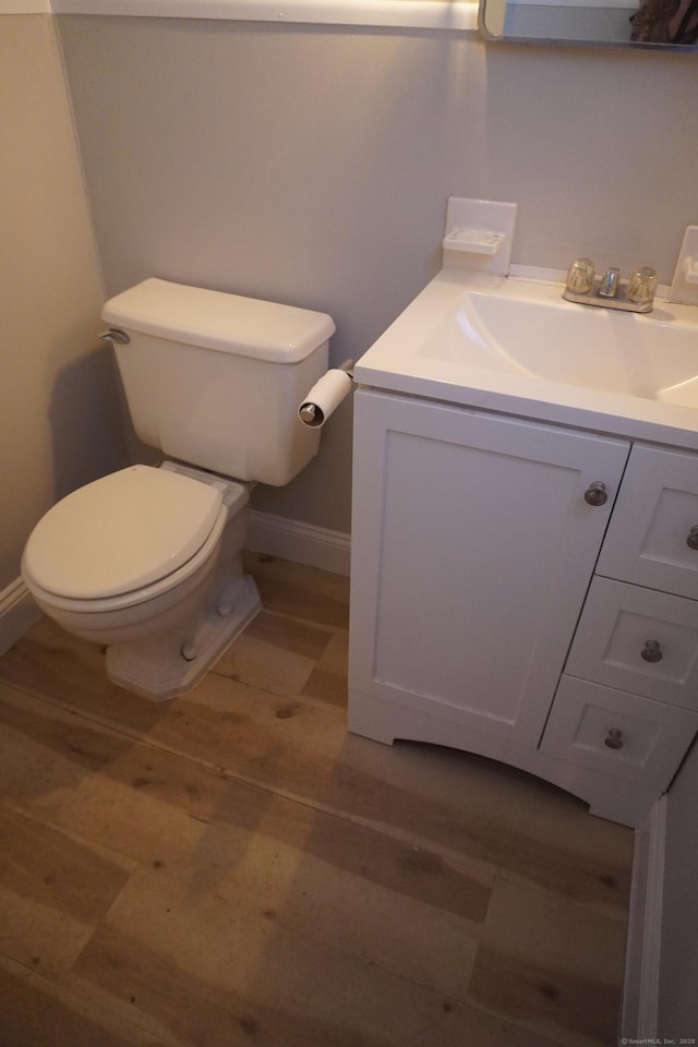 bathroom featuring toilet, vanity, baseboards, and wood finished floors