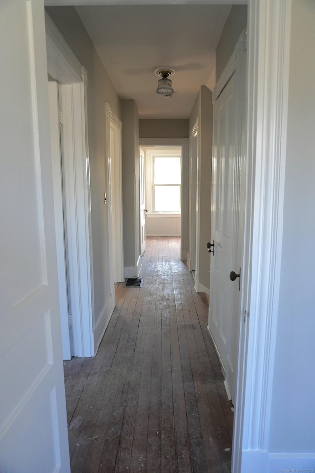 corridor featuring dark wood-style floors and baseboards