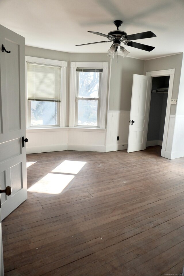 unfurnished room with wainscoting, ceiling fan, and hardwood / wood-style floors
