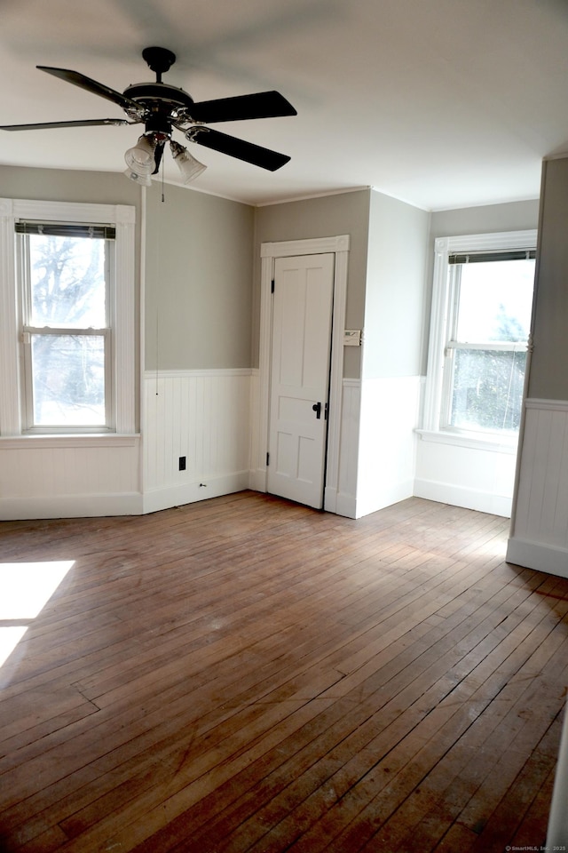 unfurnished room with hardwood / wood-style flooring, a healthy amount of sunlight, and a wainscoted wall