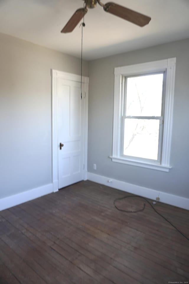 unfurnished room featuring dark wood-style floors, baseboards, and ceiling fan