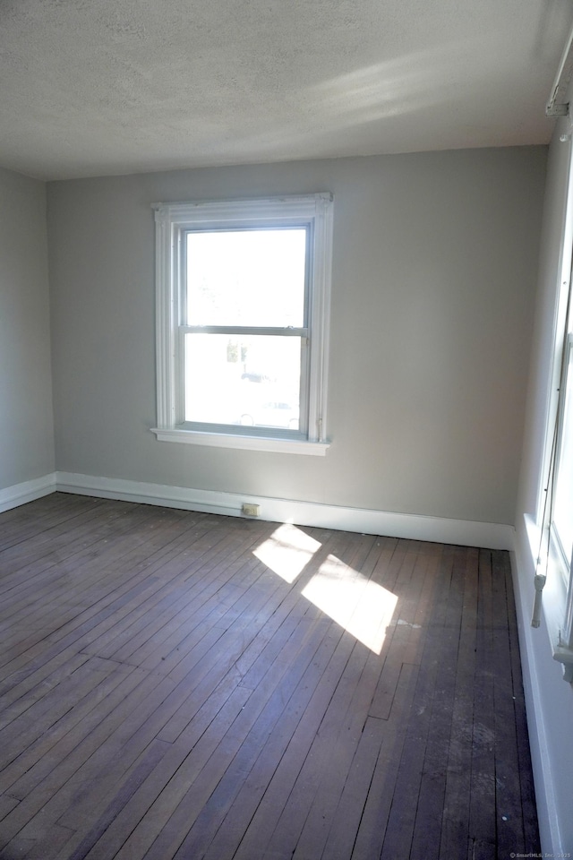 spare room featuring baseboards, a textured ceiling, and hardwood / wood-style flooring