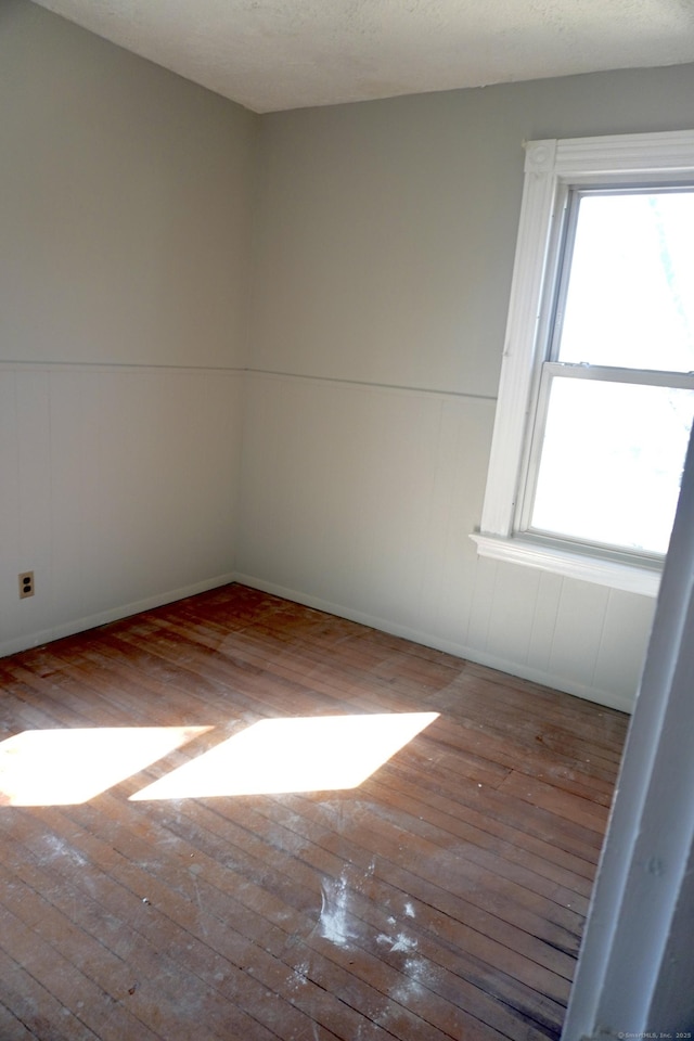 unfurnished room with a textured ceiling and hardwood / wood-style floors
