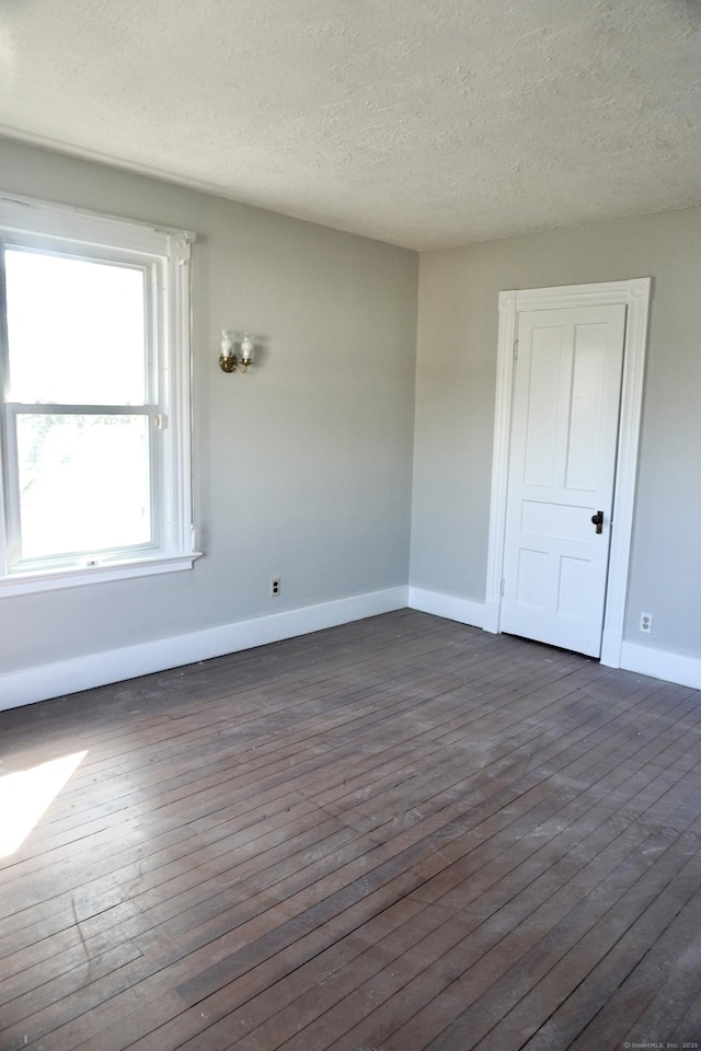 spare room with baseboards, a textured ceiling, and dark wood-style flooring