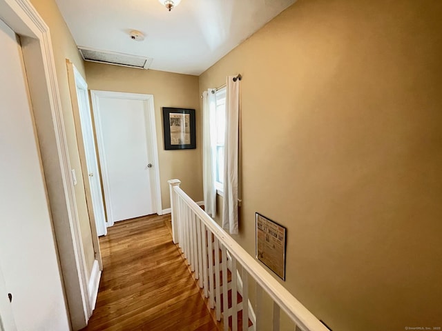 corridor featuring attic access, wood finished floors, and an upstairs landing