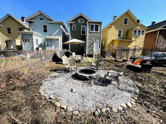 back of house with a fire pit and fence