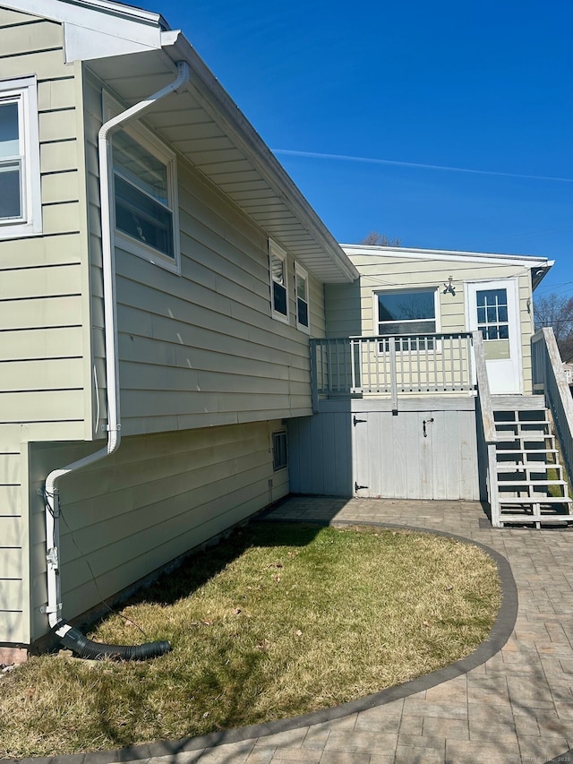 view of side of home featuring a lawn, a wooden deck, and stairs