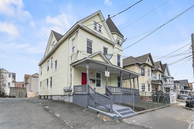 view of front of home featuring a residential view, a porch, and fence