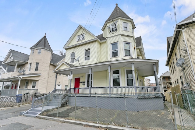 victorian house featuring covered porch and fence