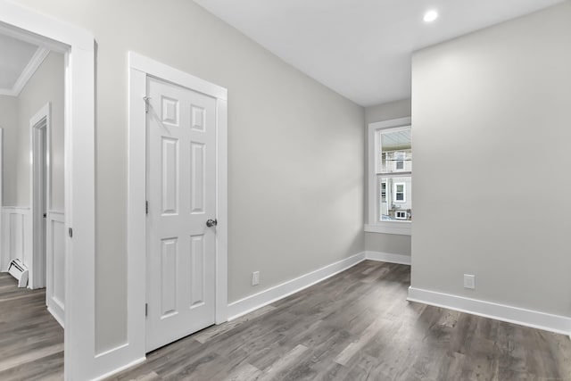 unfurnished bedroom featuring wood finished floors, baseboards, and a baseboard radiator