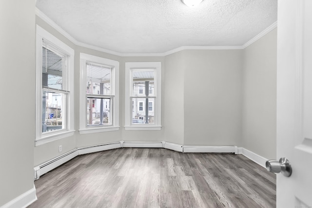 spare room featuring crown molding, wood finished floors, baseboards, and a textured ceiling