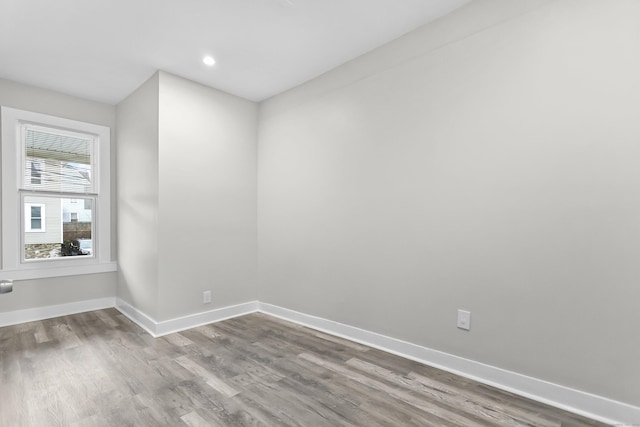 empty room featuring recessed lighting, wood finished floors, and baseboards