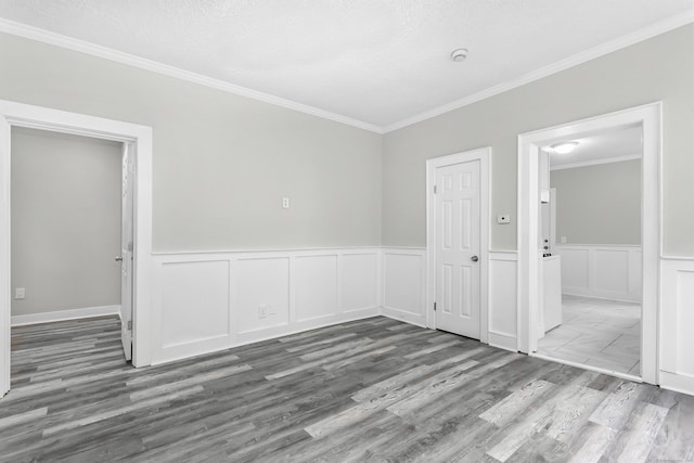 spare room featuring a wainscoted wall, crown molding, and wood finished floors