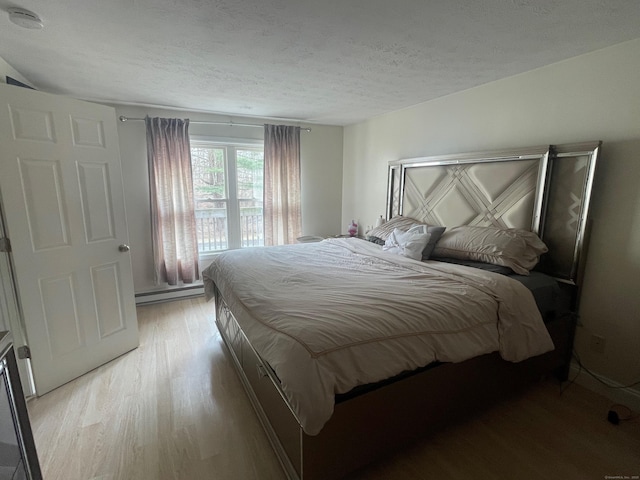 bedroom with a textured ceiling, light wood-style flooring, and a baseboard radiator