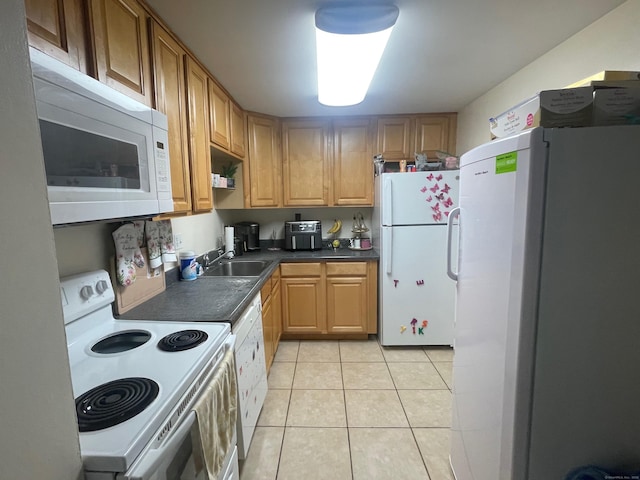kitchen with light tile patterned floors, white appliances, dark countertops, and a sink