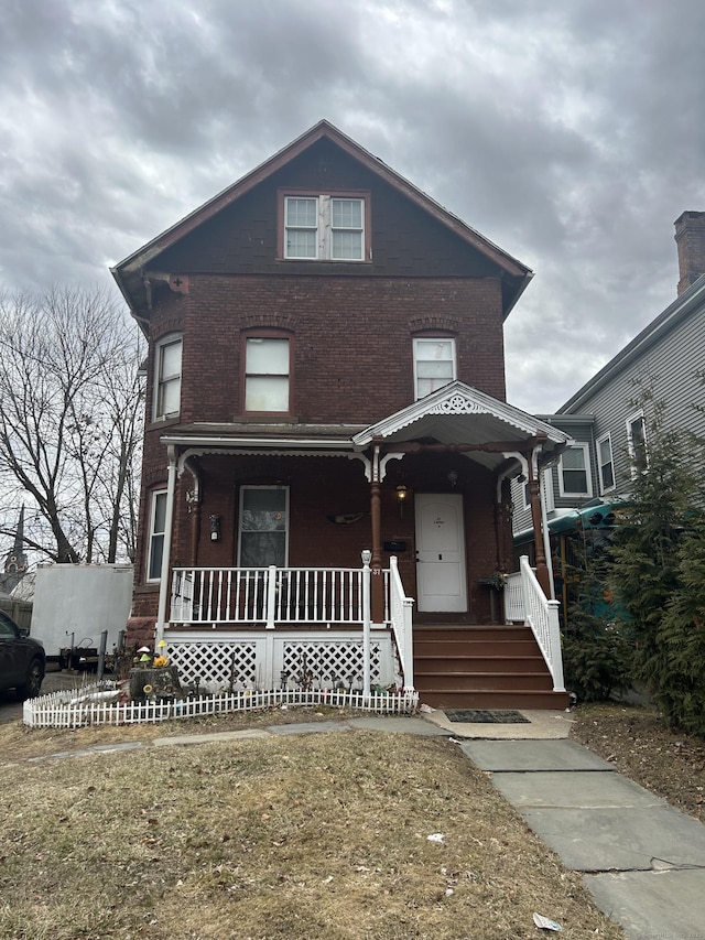 view of front of house featuring brick siding and a porch