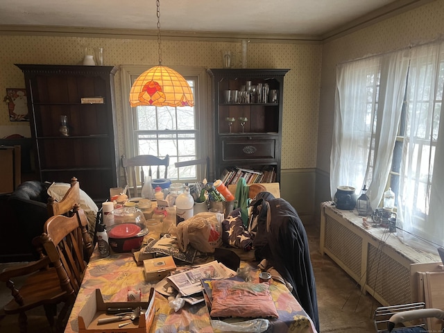 carpeted dining space featuring a wainscoted wall, radiator heating unit, wallpapered walls, and crown molding