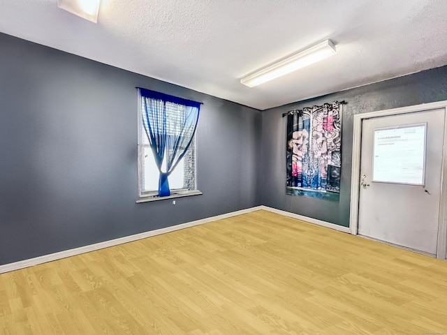 unfurnished room with wood finished floors, baseboards, and a textured ceiling