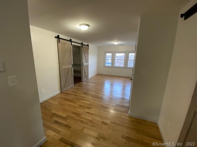 corridor featuring a barn door, baseboards, and light wood-style floors