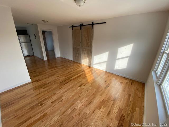 unfurnished room with a barn door, baseboards, and light wood-type flooring