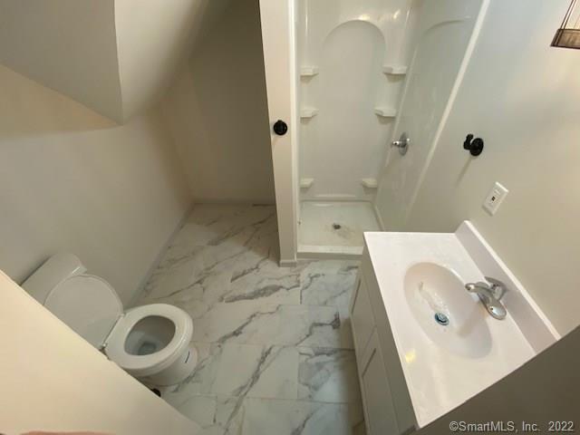 full bath with toilet, marble finish floor, a stall shower, baseboards, and vanity