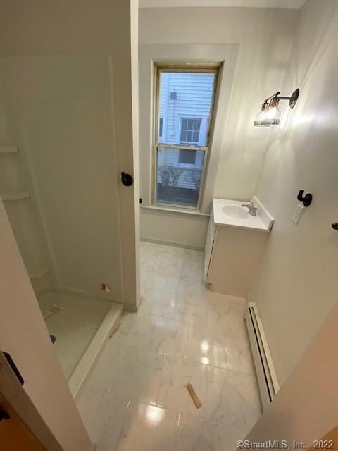 full bath with baseboards, vanity, baseboard heating, and a shower stall