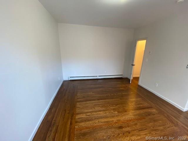 unfurnished room featuring a baseboard radiator, baseboards, and wood finished floors