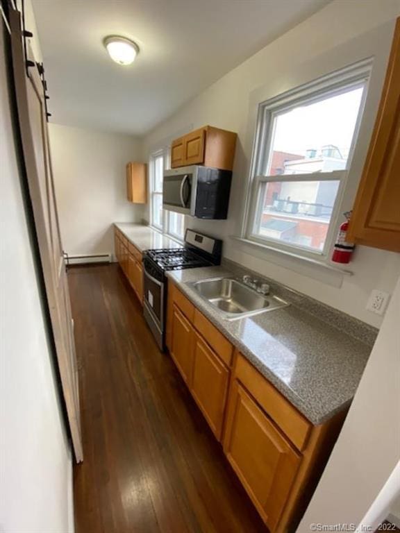 kitchen featuring a baseboard radiator, dark wood finished floors, a sink, appliances with stainless steel finishes, and brown cabinets