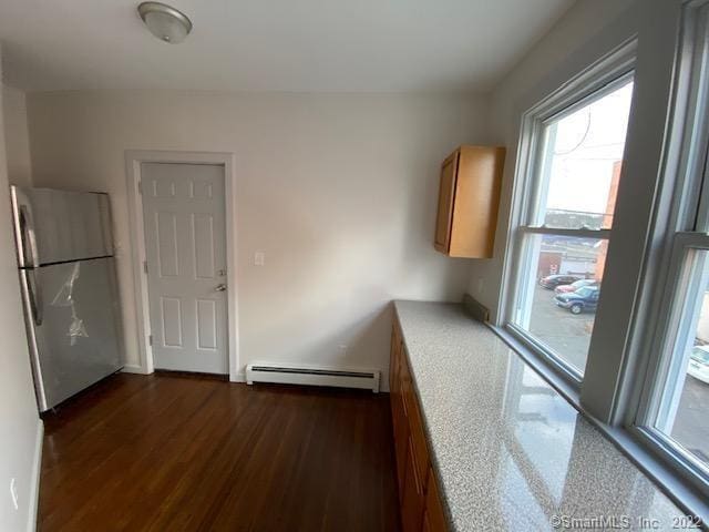 kitchen featuring brown cabinetry, freestanding refrigerator, dark wood-type flooring, light countertops, and baseboard heating