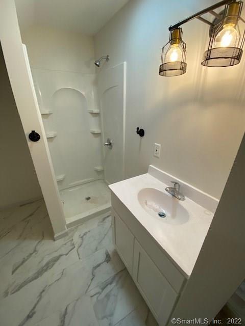 bathroom featuring marble finish floor, a stall shower, and vanity