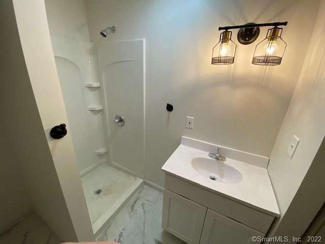 bathroom featuring vanity, marble finish floor, and a stall shower