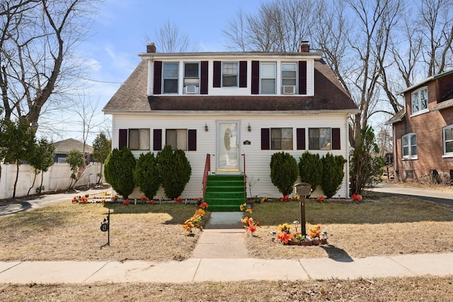 bungalow-style house featuring roof with shingles, a chimney, and fence