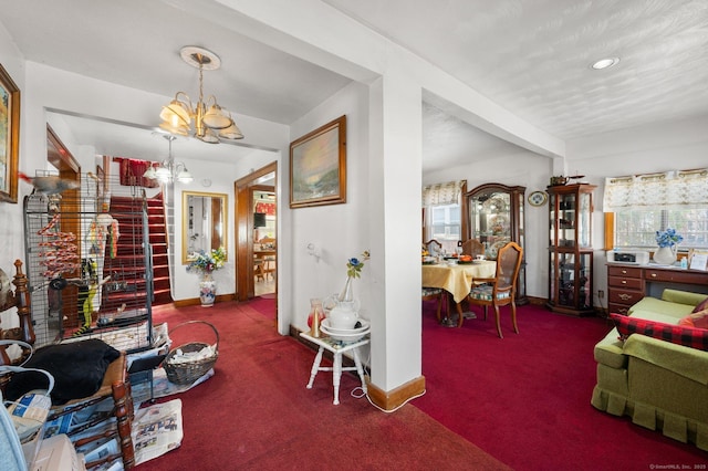 living area featuring baseboards, a chandelier, and carpet flooring