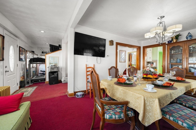 carpeted dining room featuring a chandelier and baseboards