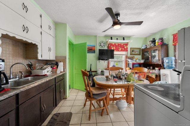 kitchen featuring a sink, tasteful backsplash, white cabinets, light tile patterned floors, and ceiling fan