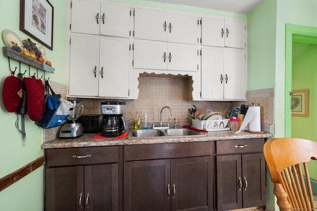 kitchen featuring dark brown cabinets, white cabinets, decorative backsplash, and a sink