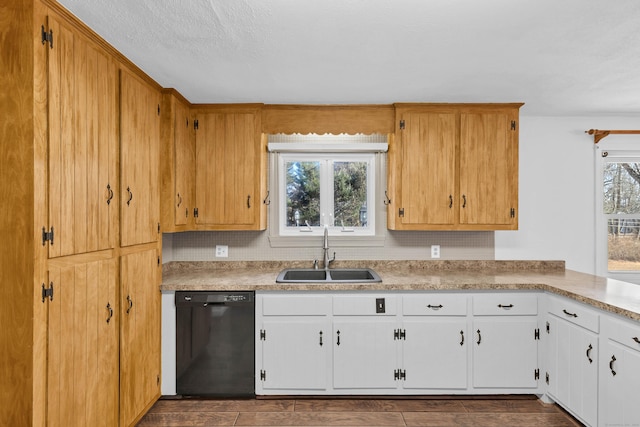 kitchen with a sink, white cabinetry, black dishwasher, and light countertops