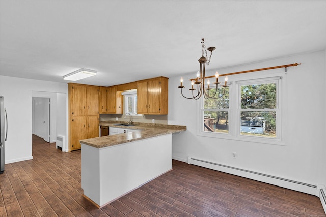 kitchen featuring a sink, a baseboard heating unit, black dishwasher, a peninsula, and dark wood-style flooring