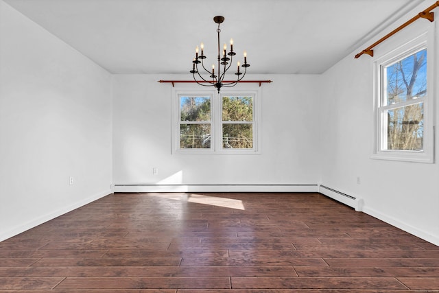 spare room with wood finished floors, plenty of natural light, and a chandelier